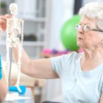 Ergotherapie am Kaffeetrichter Erfurt - Therapeutin erklärt älterer Dame am Skelett